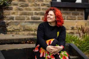 Woman with red hair sitting on steps outside.