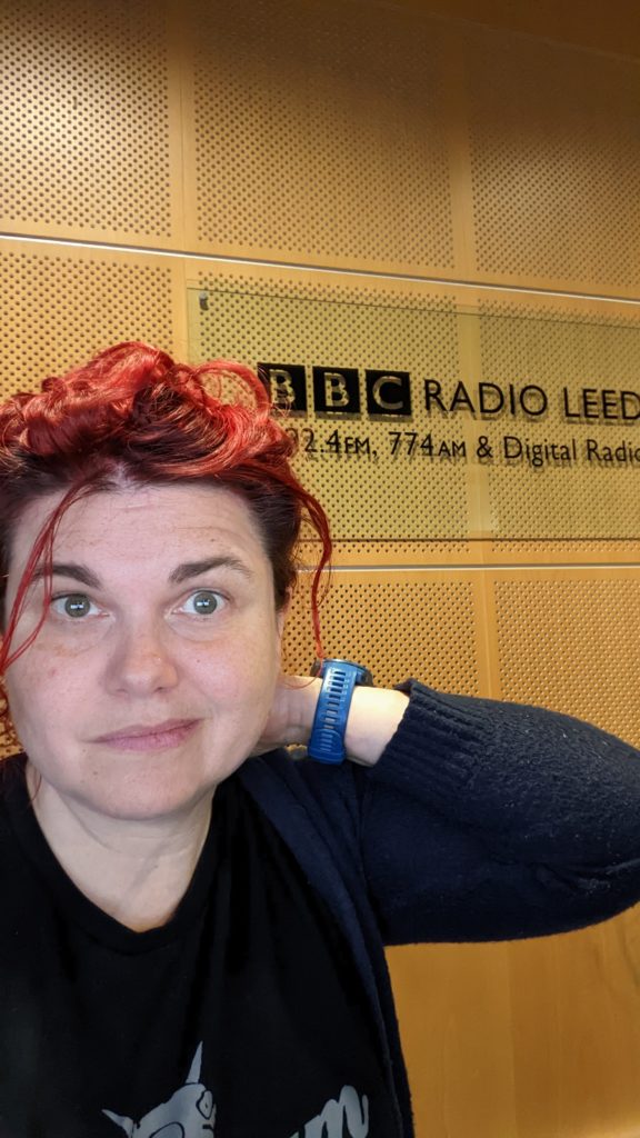 Katie making a silly face in front of BBC Radio Leeds sign.