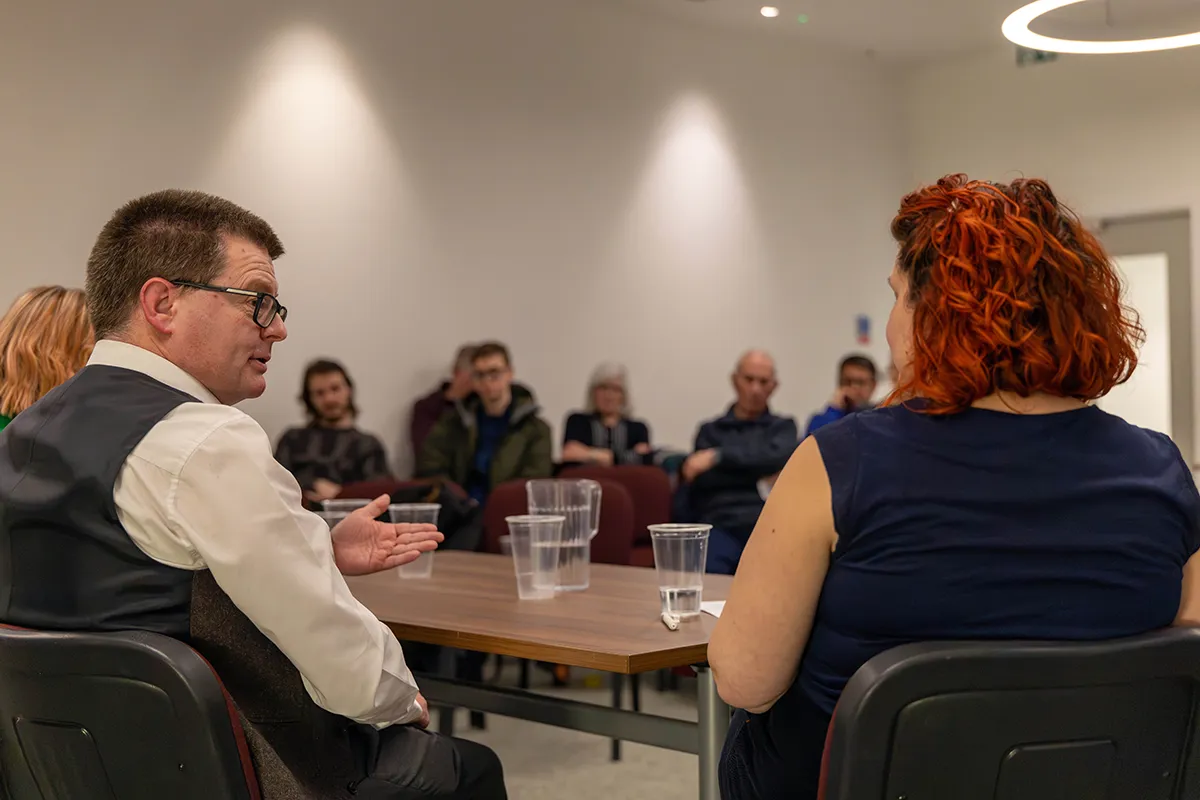 Speakers on a panel addressing a room full of people.